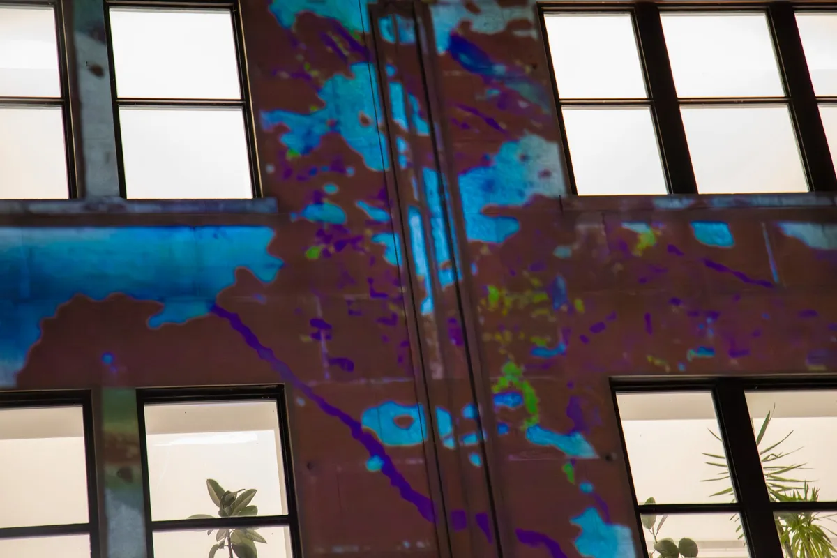 Close view of the projection — electric blue and cyan washing across the stone between lit window bays.