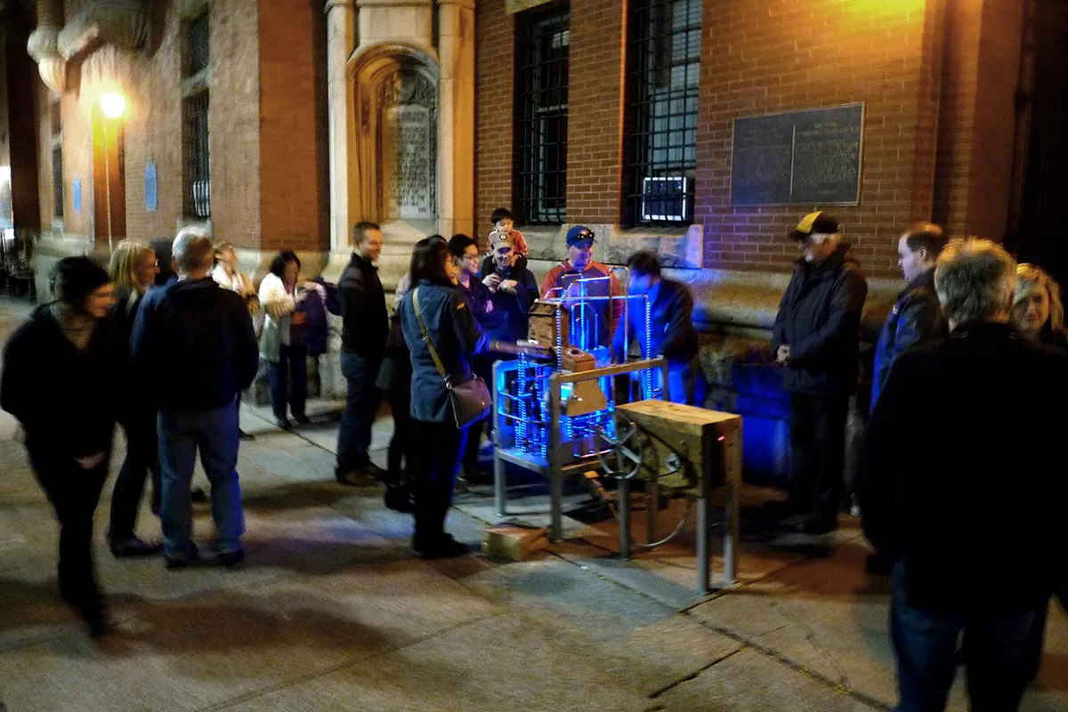 Visitors gathered around Navitas at an evening art crawl, LEDs glowing blue.